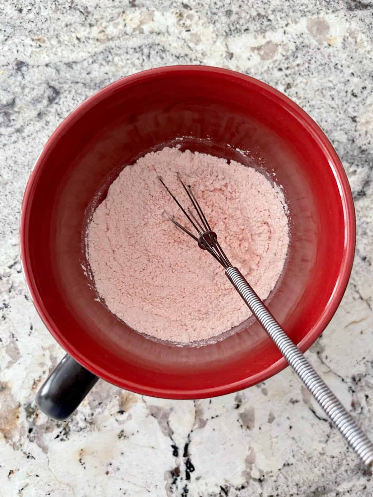 Whisking flour, baking powder, sweetener and raspberry Jell-o powder in large mug.