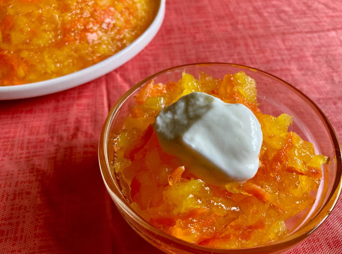 Pineapple Carrot Jello salad in small glass bowl topped with dollop of yogurt.