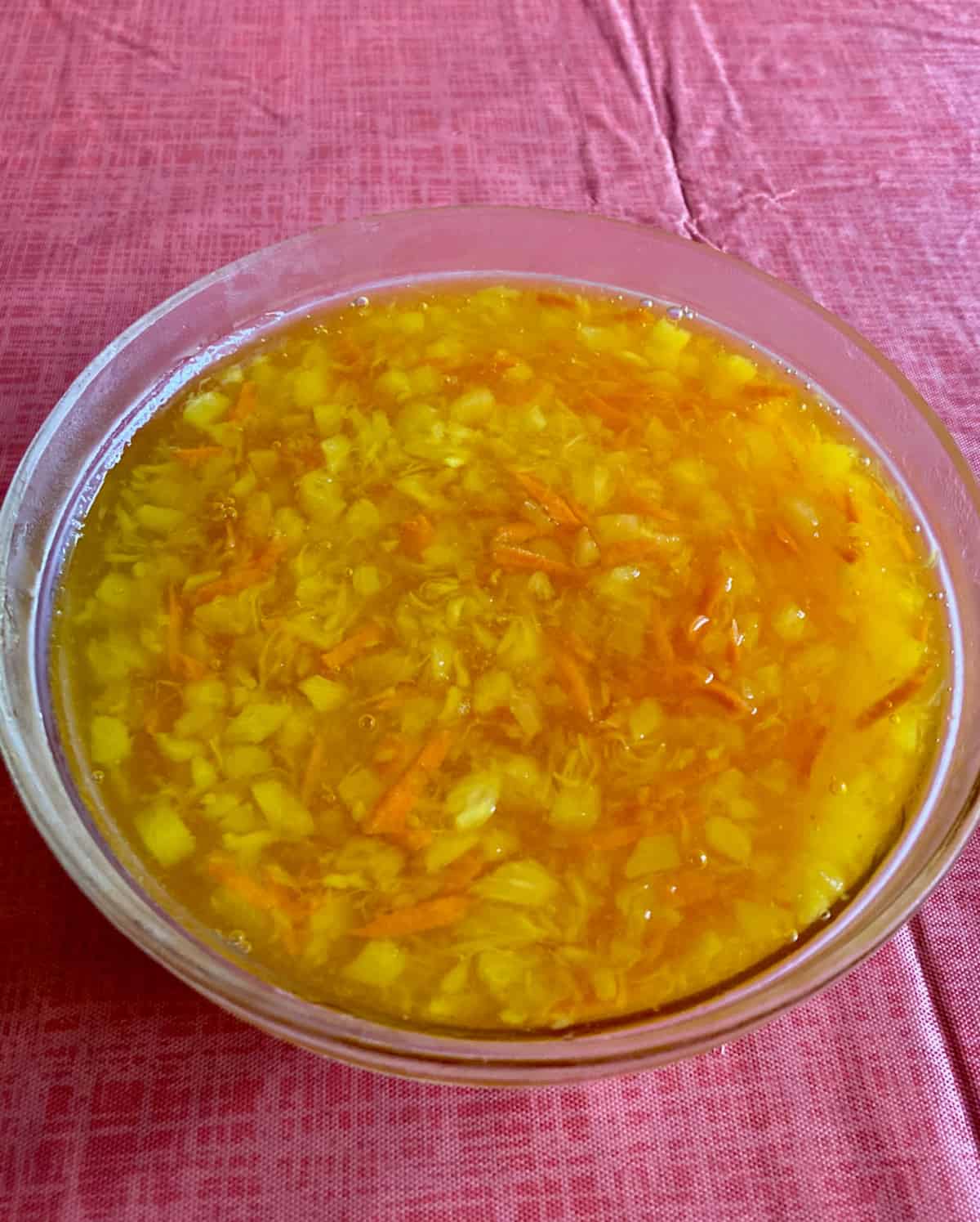Refrigerated Sunshine Salad with lemon gelatin, shredded carrots and crushed pineapple in glass bowl.