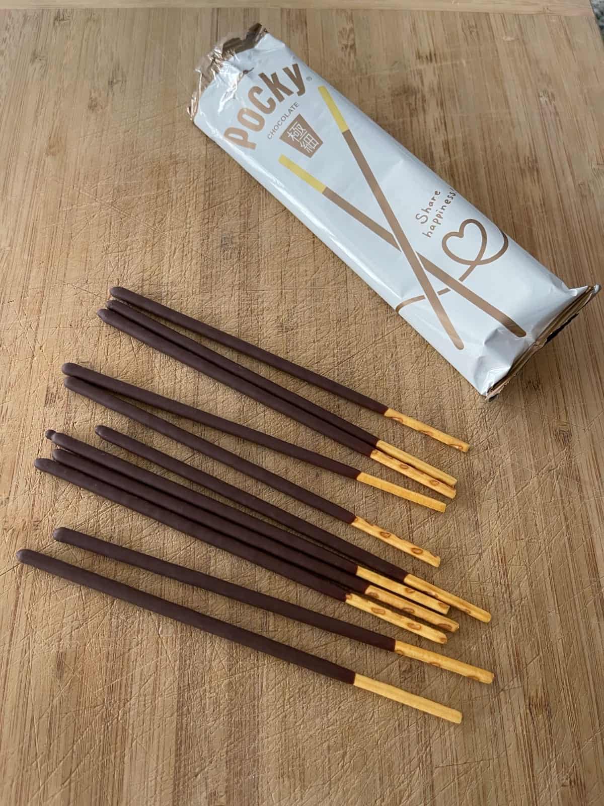Package of chocolate Pocky sticks on wood cutting board.