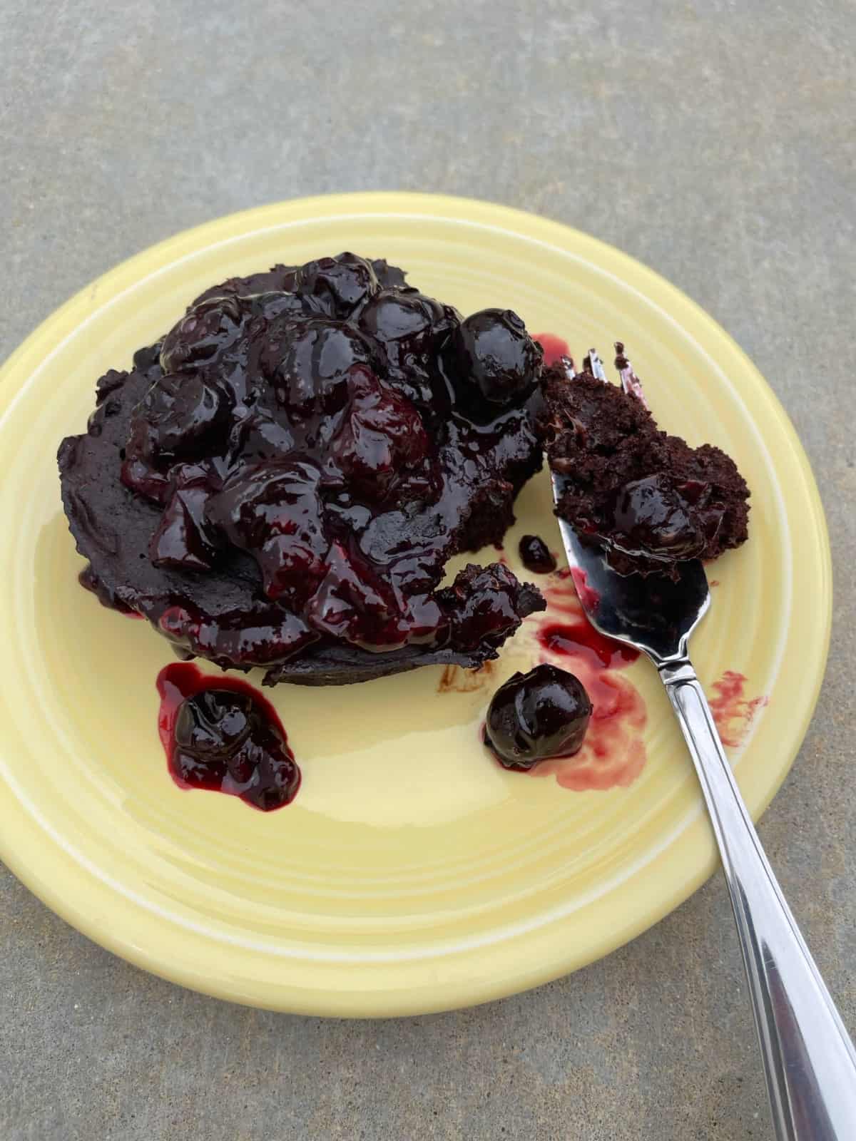 Microwave Black Forest Chocolate Cake on yellow dessert plate with fork.