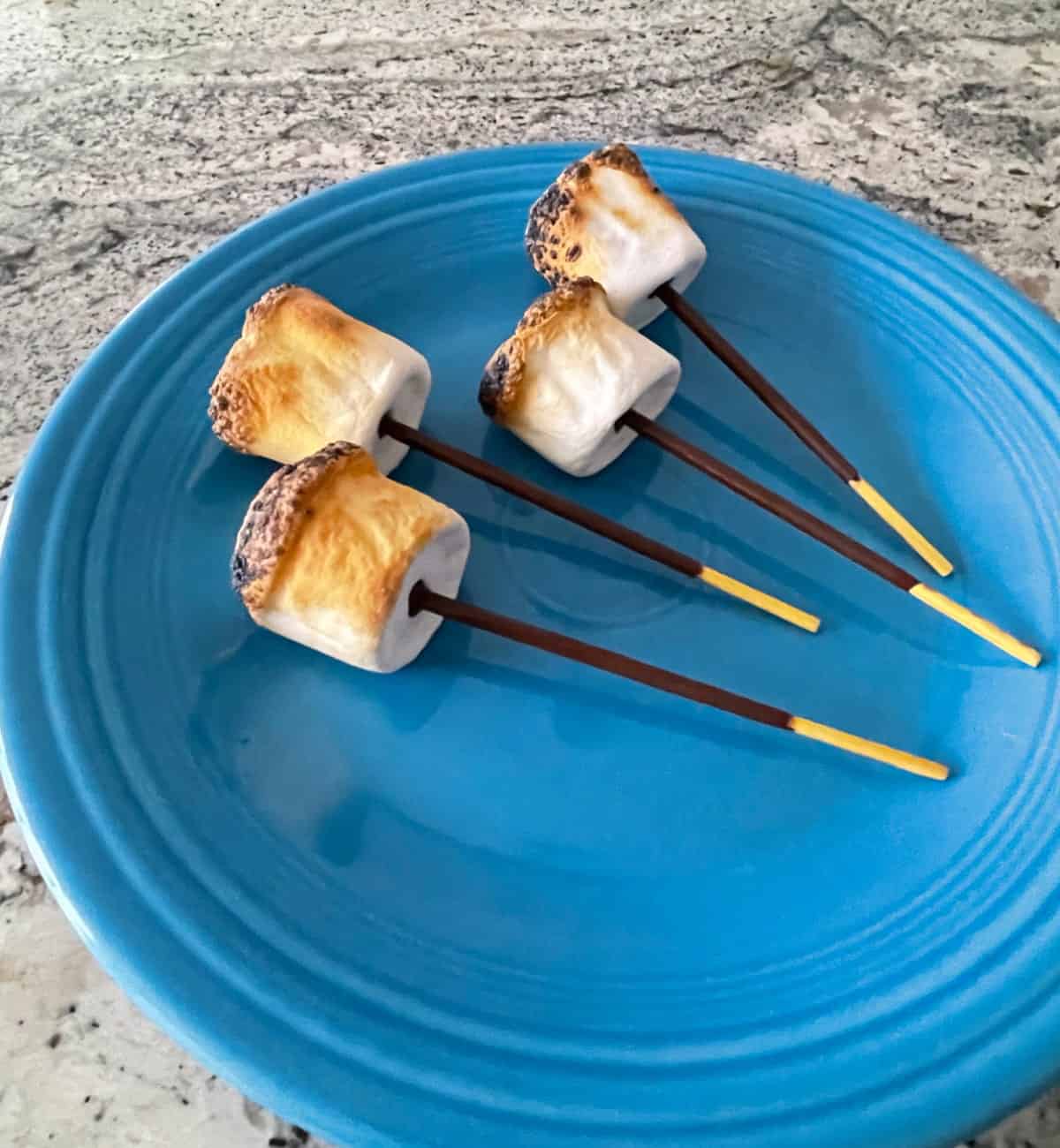 Chocolate Pocky S'mores Pops on blue serving plate.