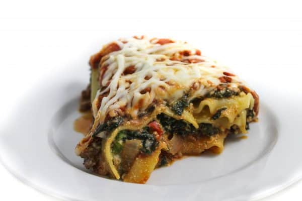 Pice of spinach beef lasagna on small white plate.