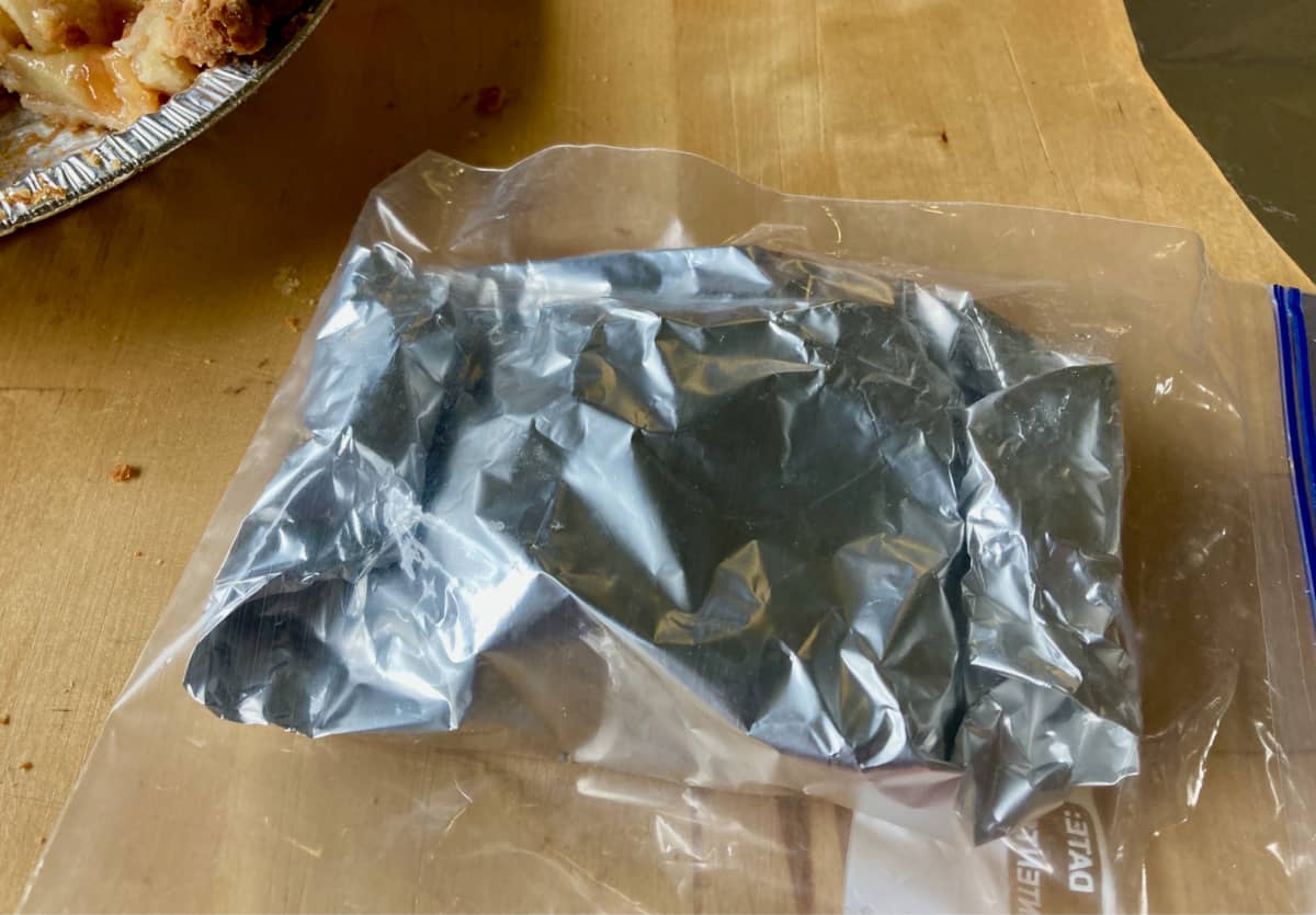Slice of apple pie wrapped in foil and sealed in ziplock plastic bag.