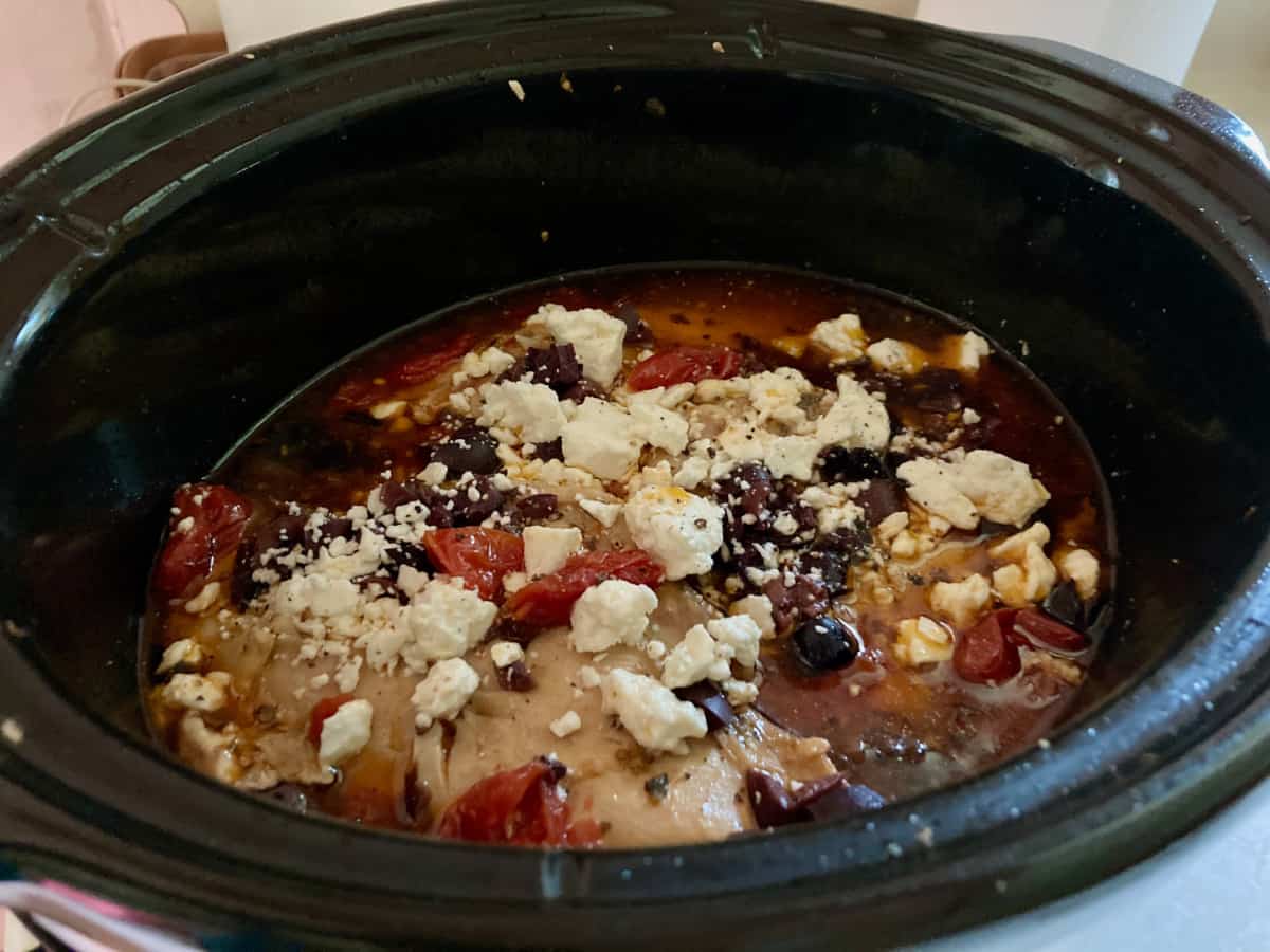 Greek CrockPot Chicken with Feta and Tomatoes in black crockpot.