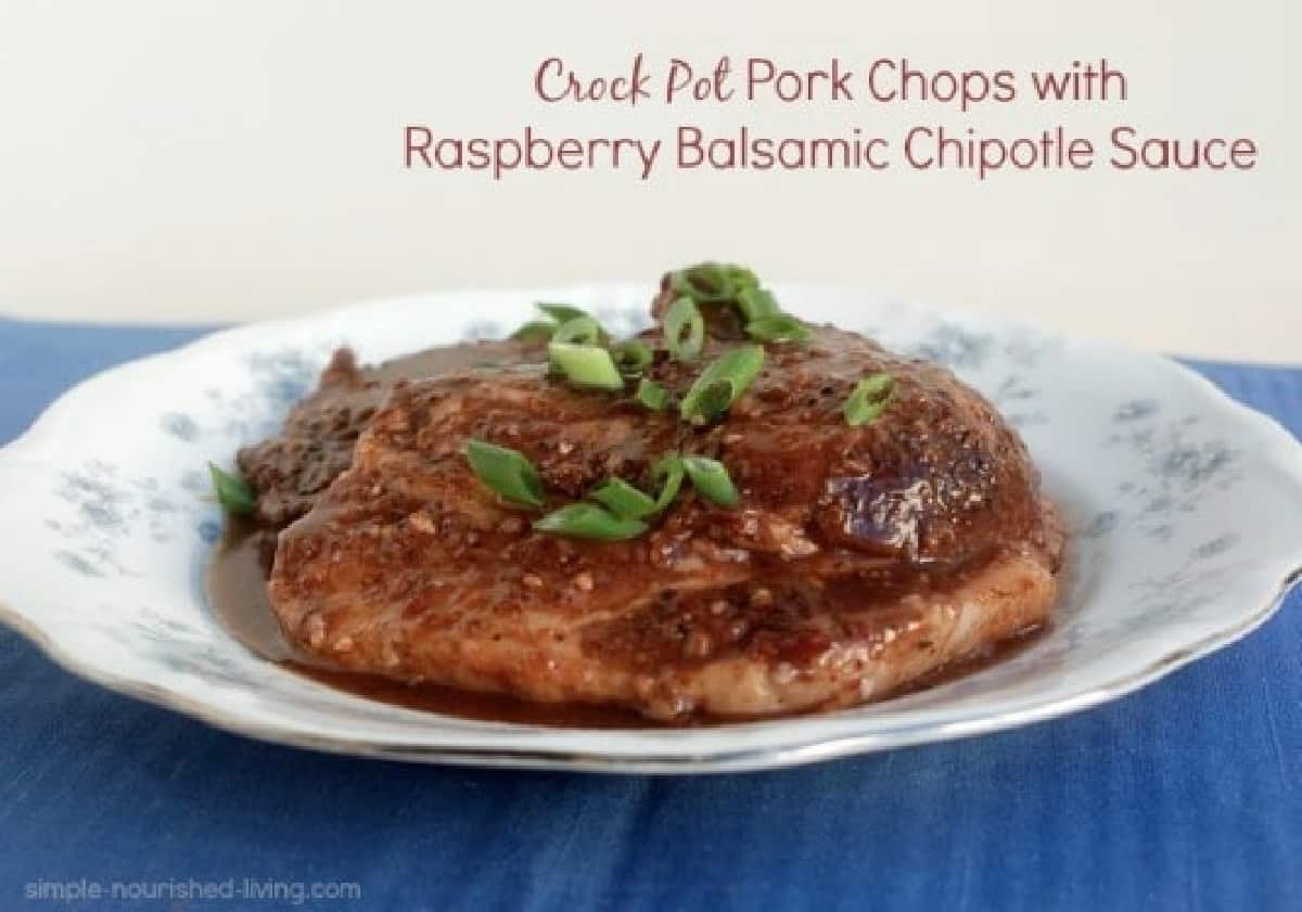 Crock Pot Pork Chops topped with raspberry chipotle sauce and sliced green onions on China.