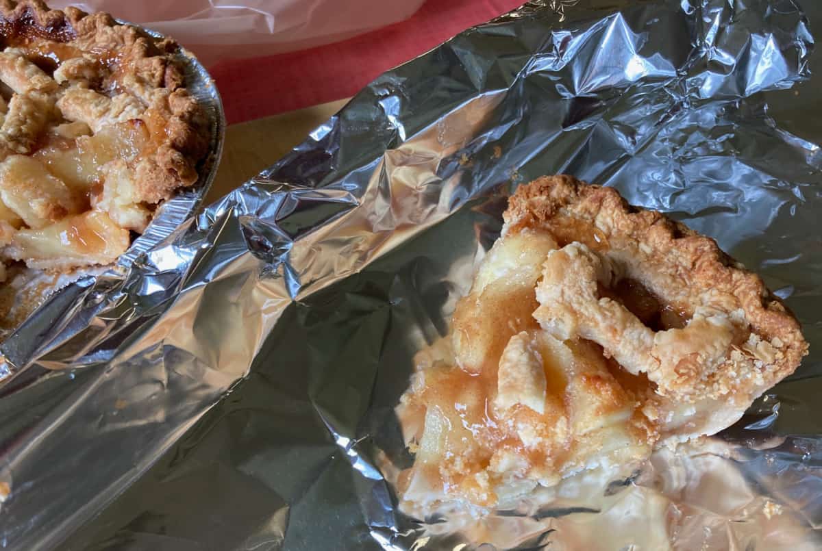 Wrapping slice of homemade apple pie in aluminum foil.