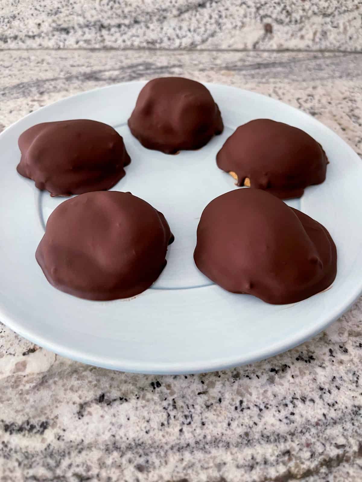 Πέντε αφράτα μπισκότα marshmallow σοκολάτας σε μικρό μπλε πιάτο σερβιρίσματος.