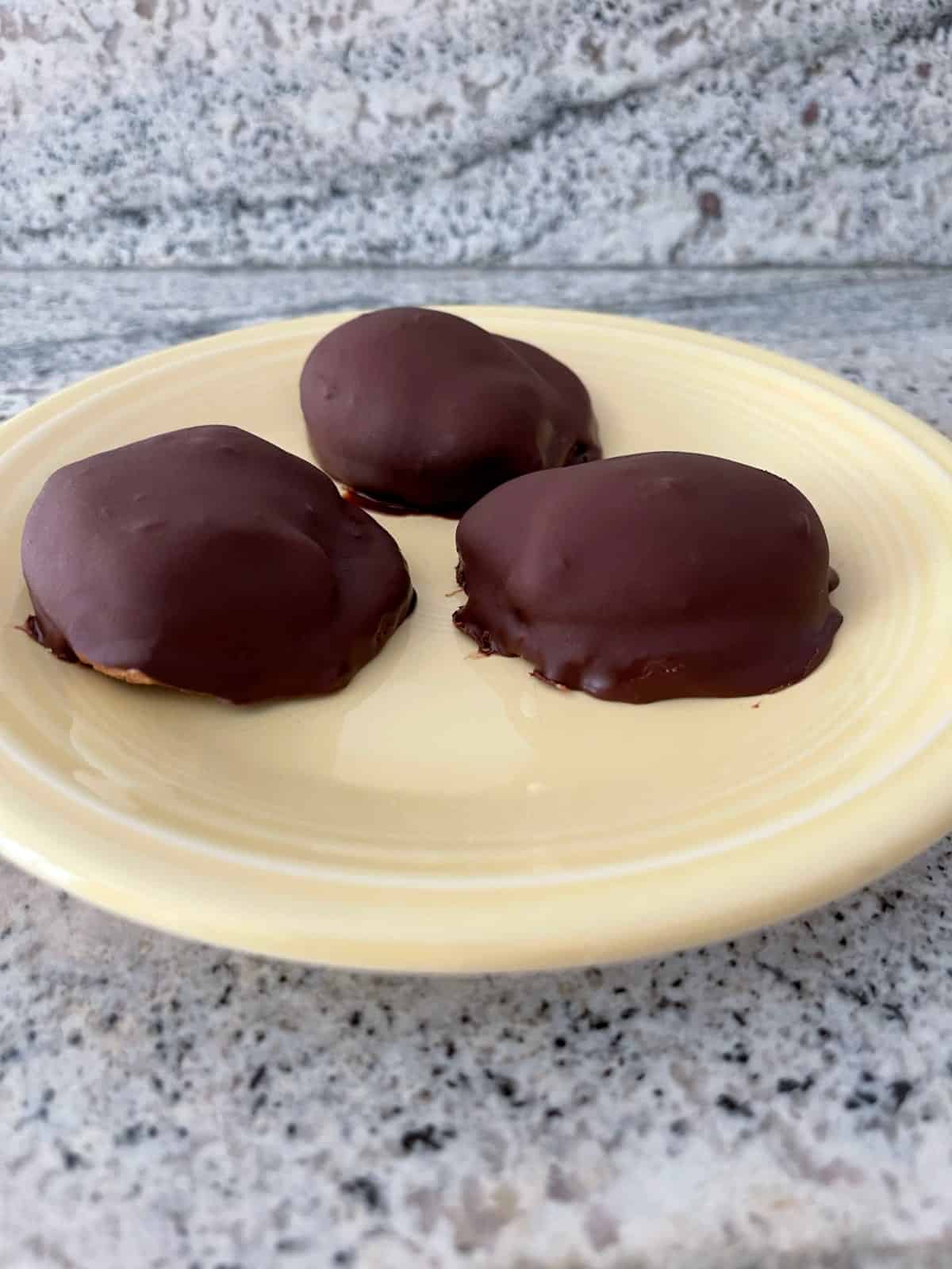 Τρία αφράτα μπισκότα marshmallow σοκολάτας στο κίτρινο πιάτο.