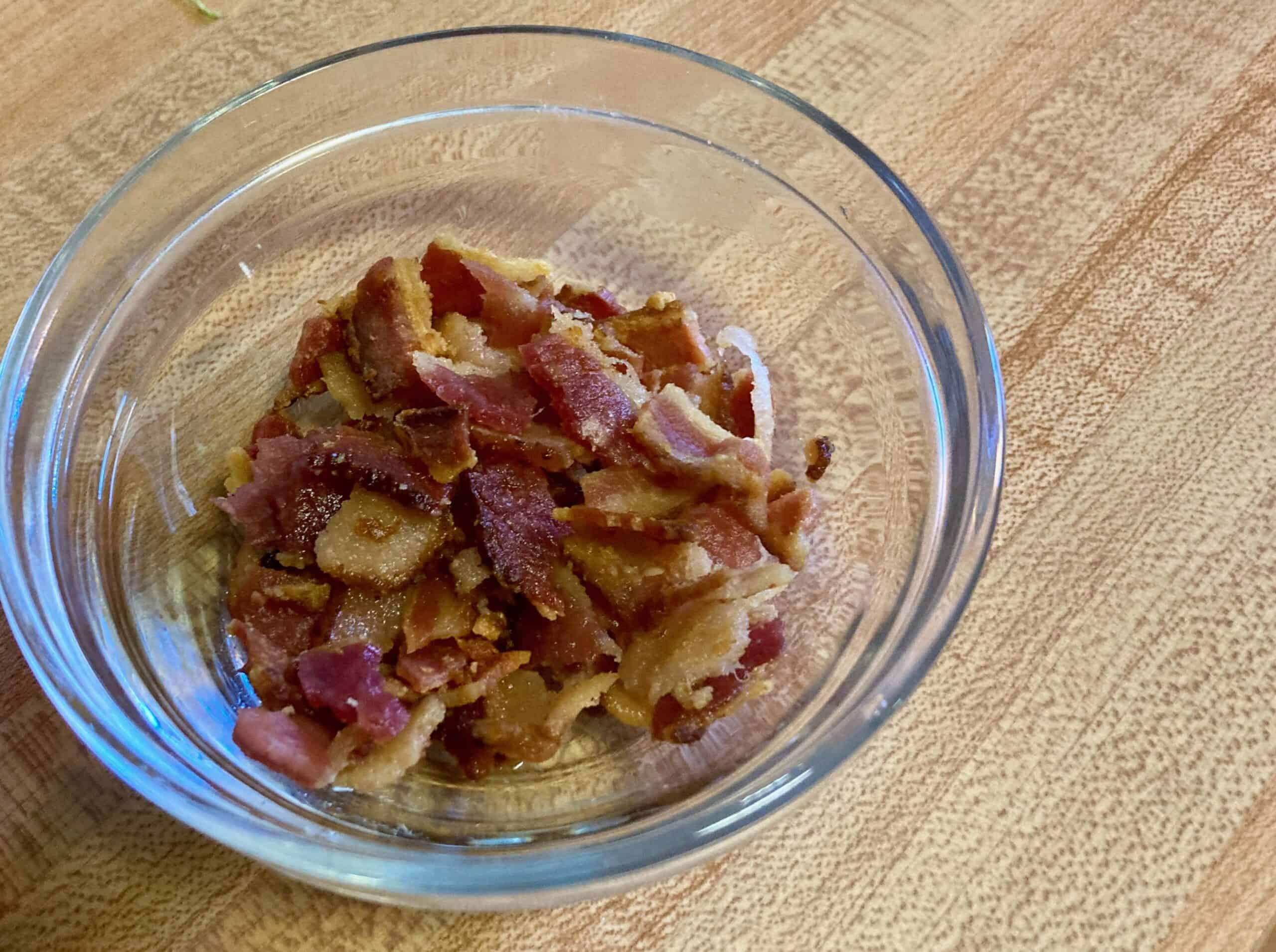 Crumbled bacon in small glass bowl.
