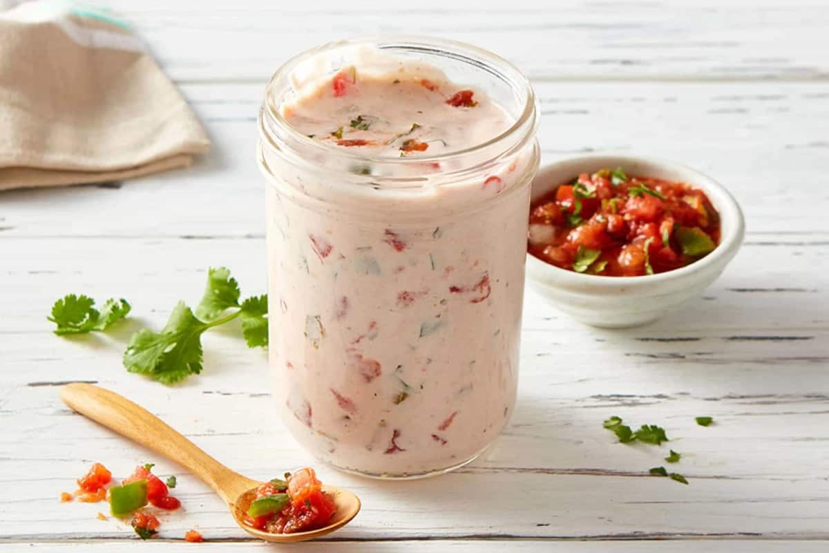 Jar of homemade salsa ranch dressing near small bowl of fresh tomato salsa.