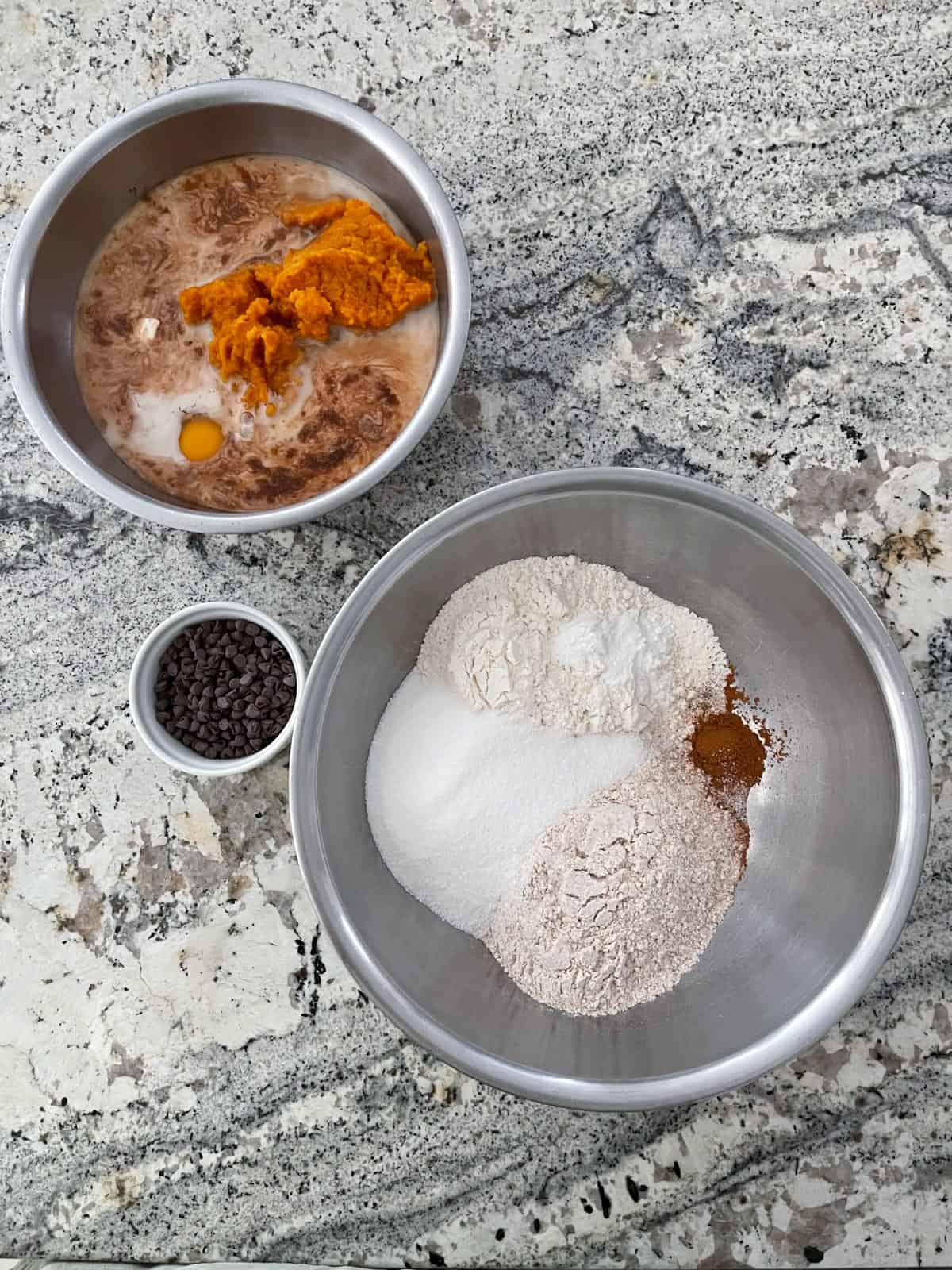 Wet ingredients and dry ingredients in two separate mixing bowls for making pumpkin chocolate chip cake.