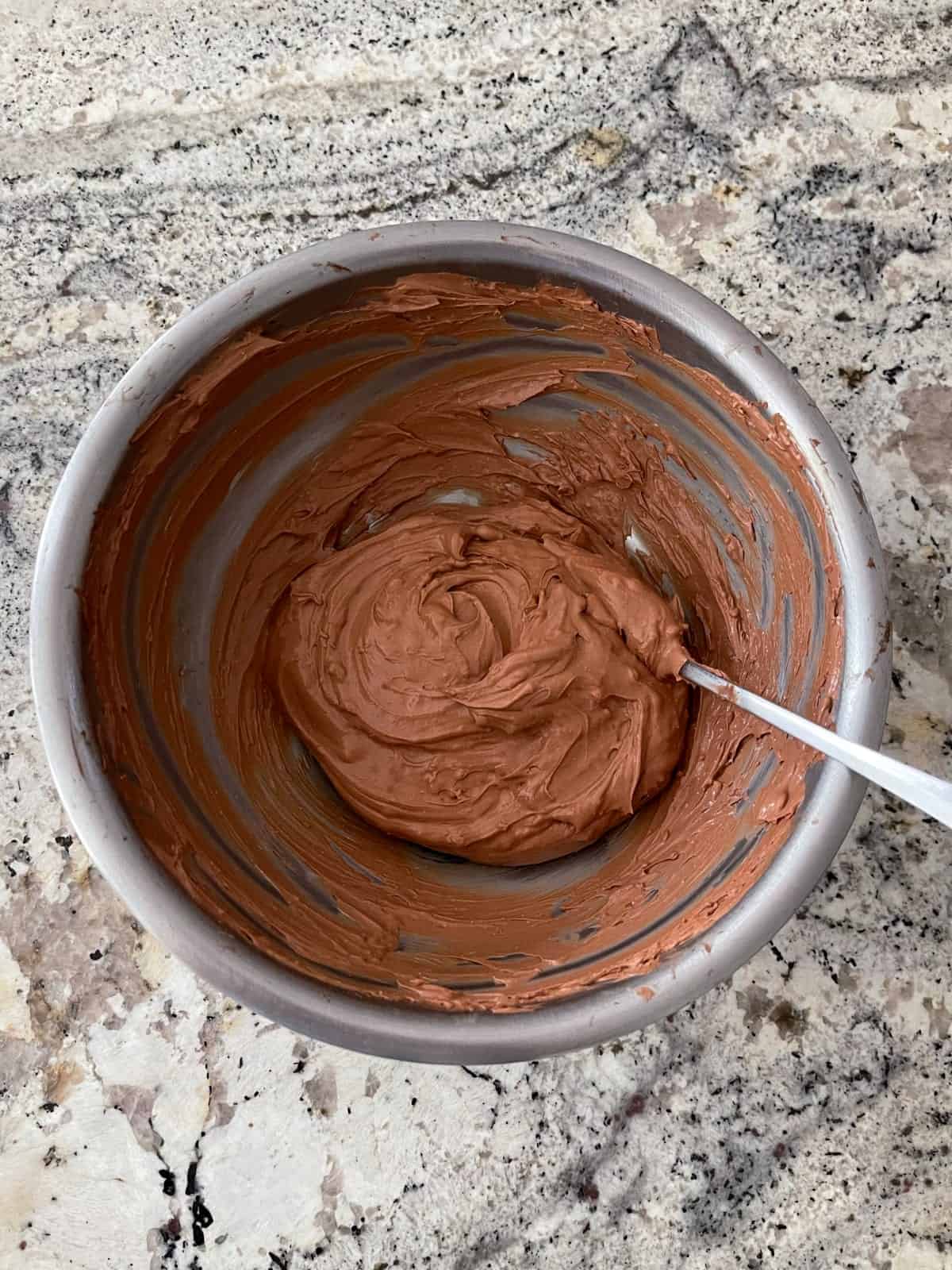 Stirring together spoonable chocolate cheesecake ingredients in mixing bowl until creamy and smooth.
