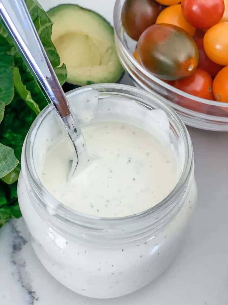 Fresh vegetables with jar of homemade ranch dressing with spoon.
