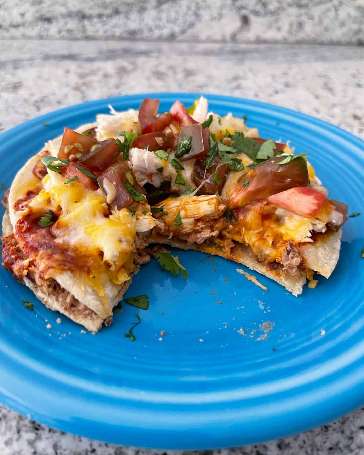 Mexican pizza with chicken and chopped cilantro on blue plate.