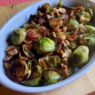 skillet roasted brussels sprouts with bacon in oval white ceramic dish