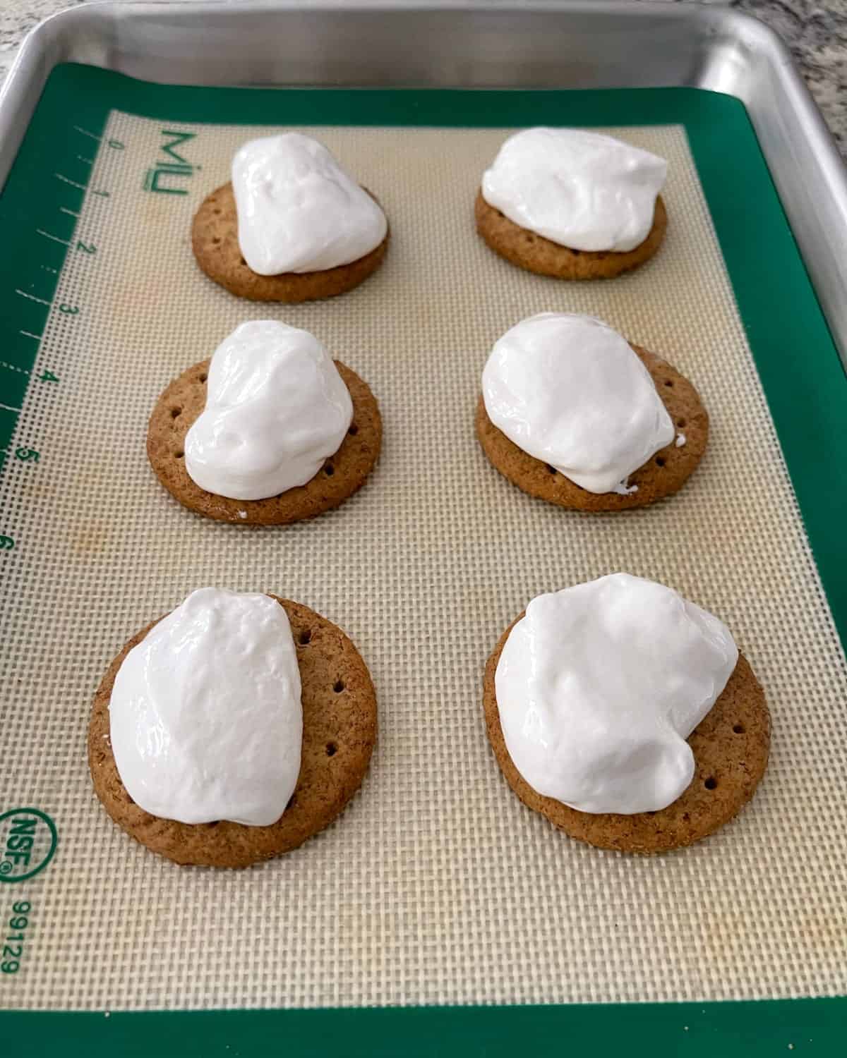 Carr's whole wheat crackers topped with dollop of marshmallow creme on silicone lined cookie sheet.