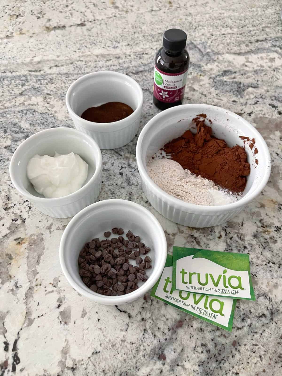Ingredients including instant coffee powder, vanilla extract, whole wheat flour, dark cocoa powder, Greek yogurt, mini chocolate chips and Truvia packets.
