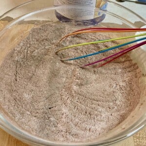 glass bowl with sugar free hot cocoa mix ingredients and whisk