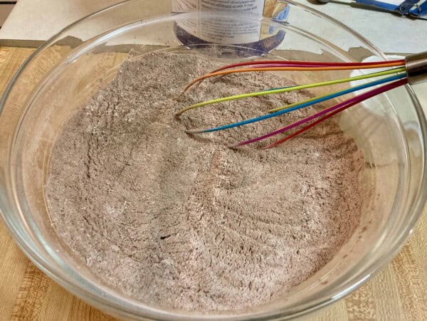 glass bowl with sugar free hot cocoa mix ingredients and whisk