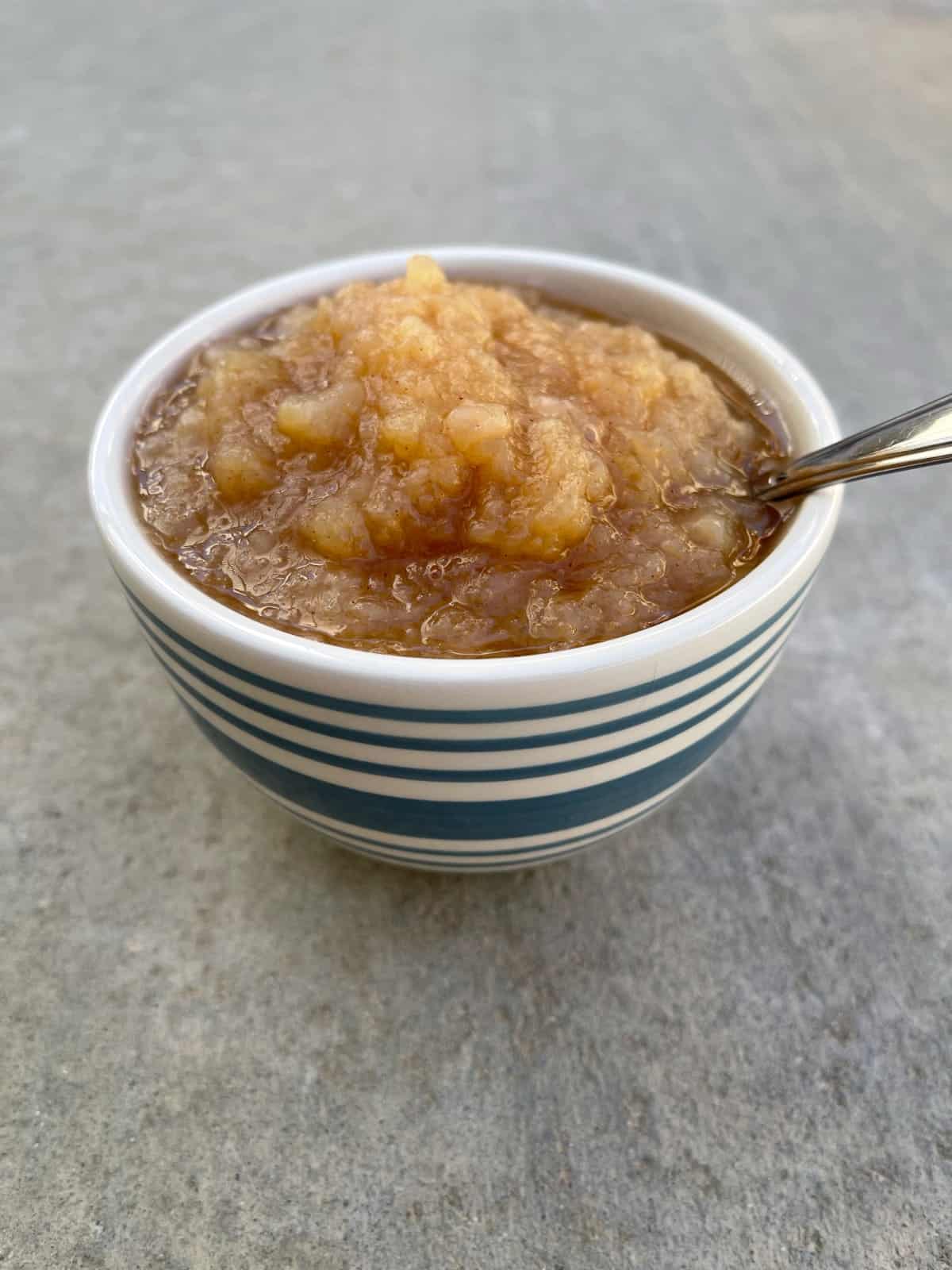 Instant Pot σάλτσα μήλου κανέλας σε μικρό μπολ με κουτάλι.