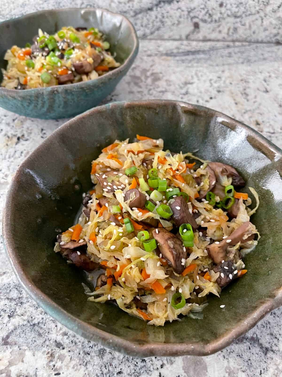 Instant pot vegetarian egg roll bowls topped with sesame seeds and sliced green onion in two green ceramic bowls.