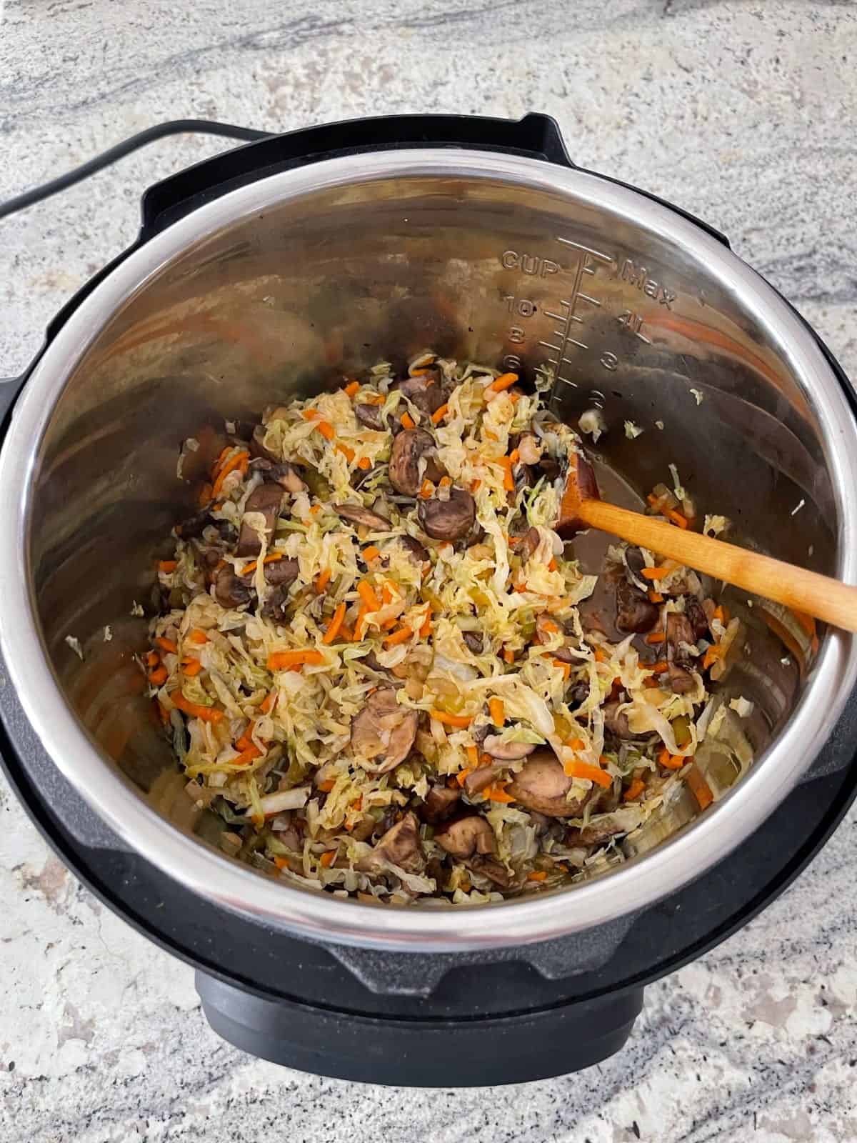 Stirring fresh cooked vegetarian egg roll bowl in Instant Pot to combine ingredients.