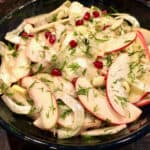 Sliced apple and fennel salad with pomegranate seeds and dill in ceramic bowl