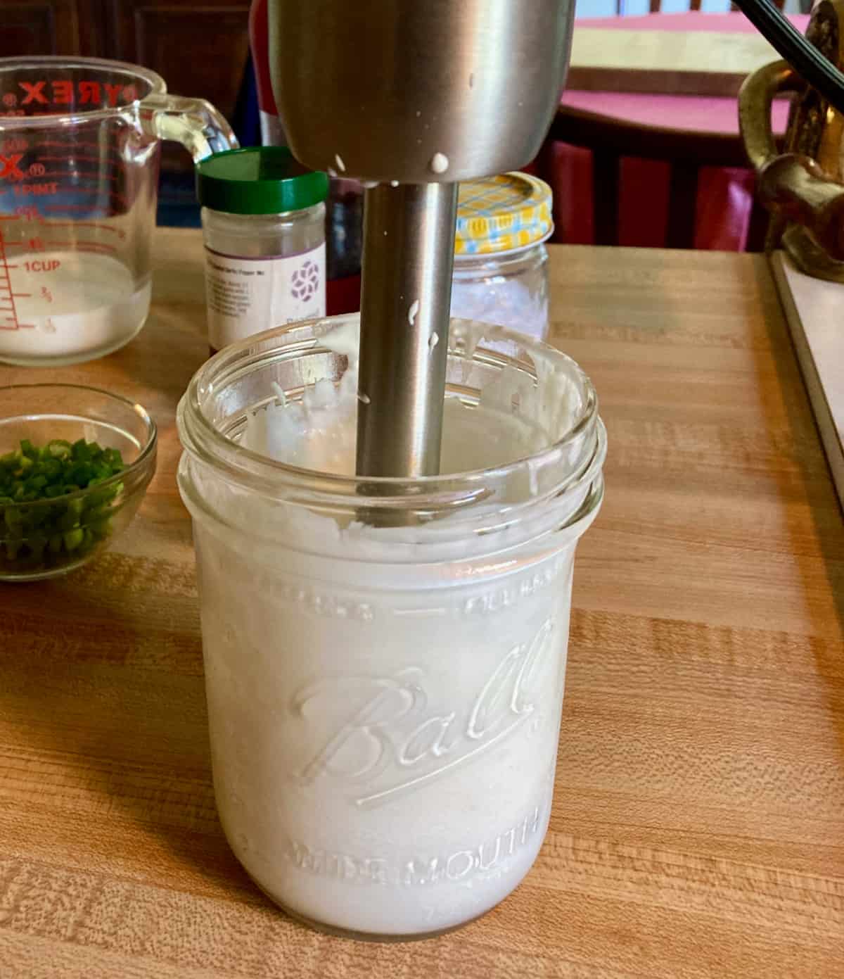Blending cottage cheese with immersion blender in mason jar.