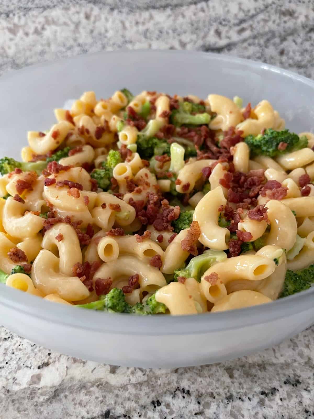 Broccoli bacon macaroni and cheese in white serving dish.