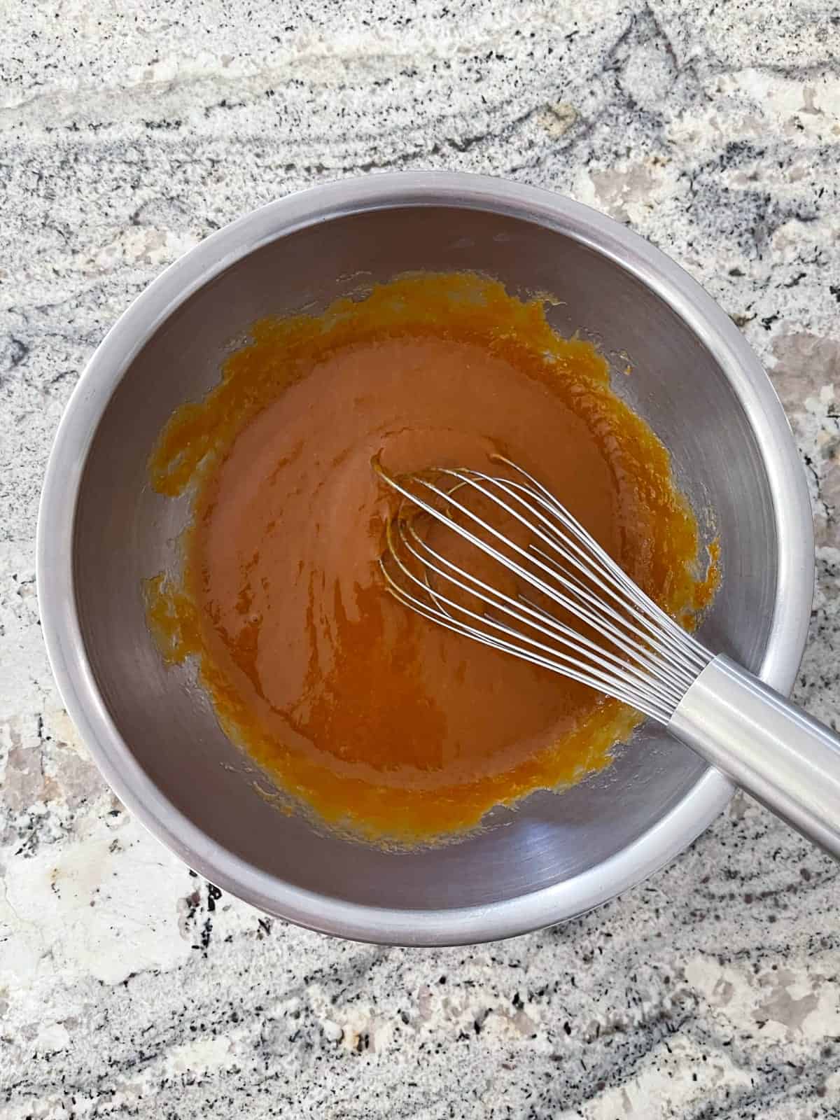 Whisking pumpkin puree, brown sugar, eggs, oil and molasses in mixing bowl.