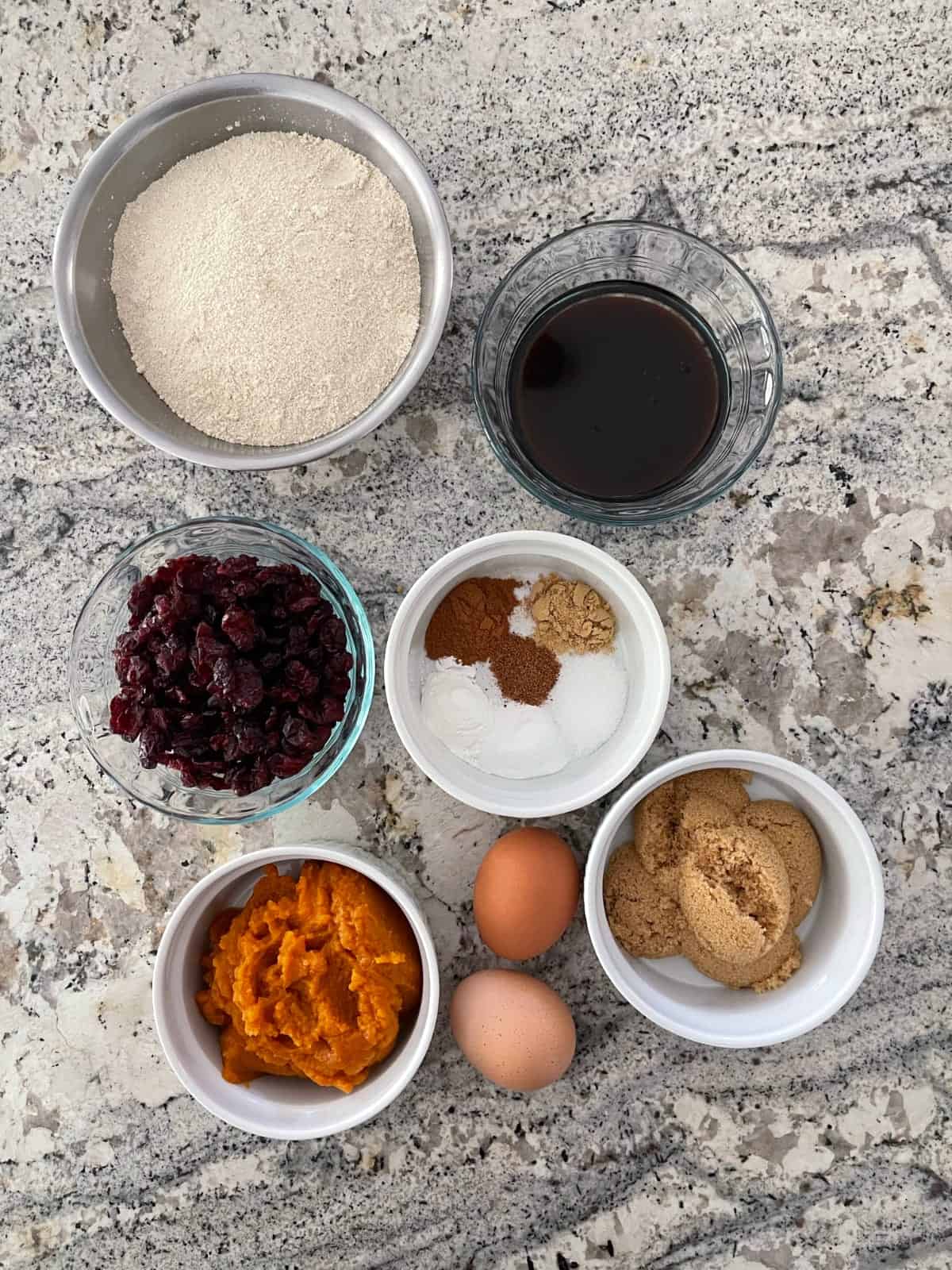 Quinoa flour, molasses, dried cranberries, pumpkin puree, eggs and brown sugar for making cookies.