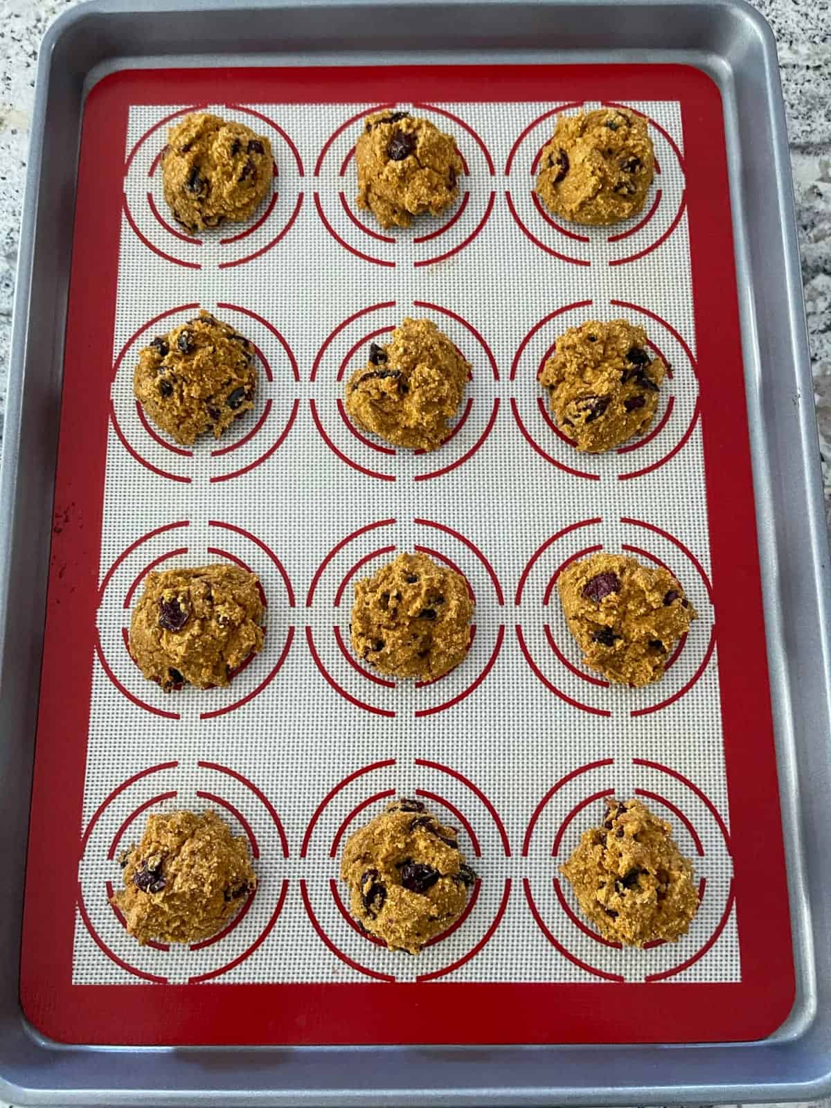 Unbaked pumpkin quinoa cranberry cookies on baking sheet.