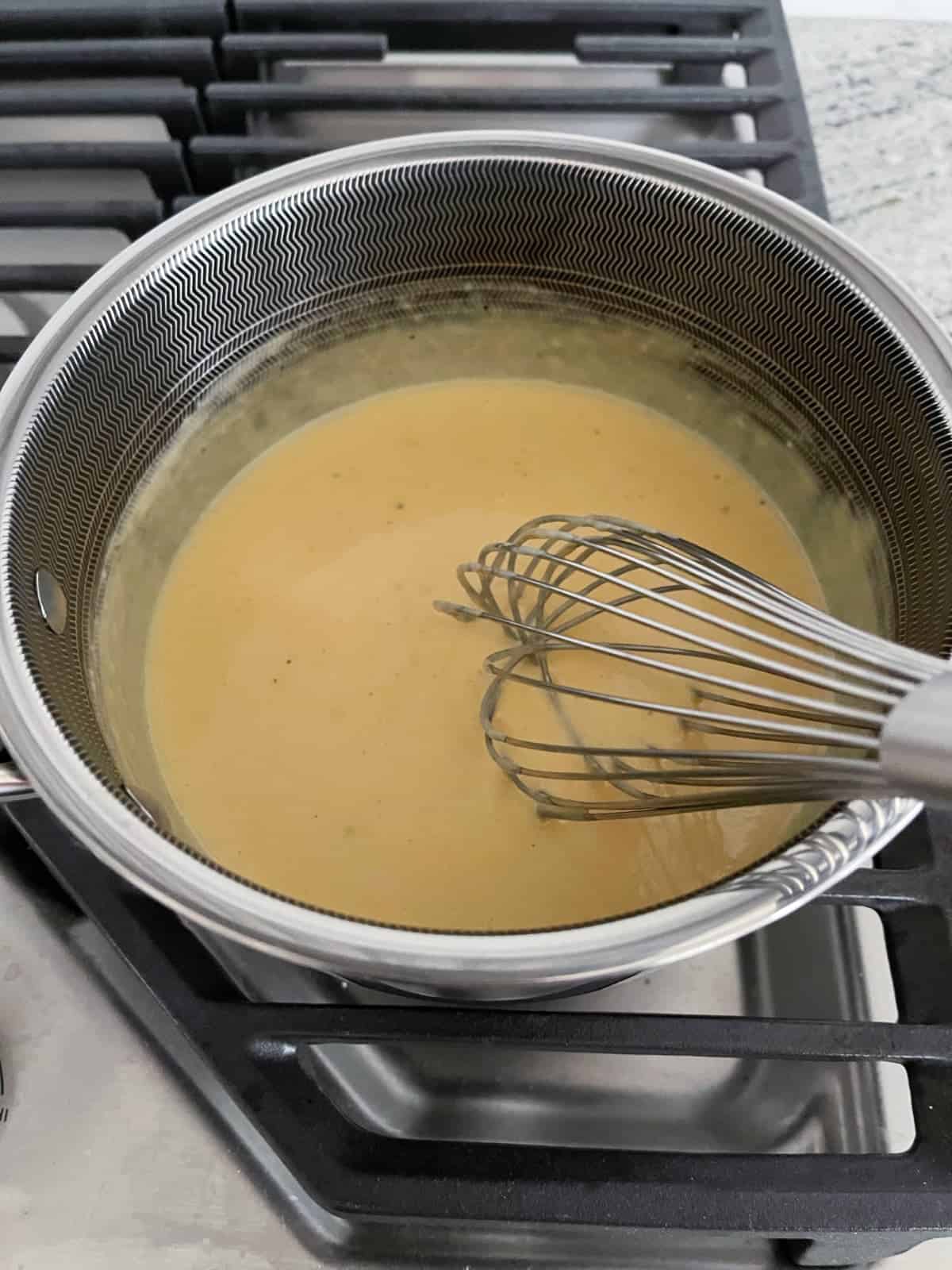 Χτυπώντας τη σάλτσα τυριού μακαρόνια στην κατσαρόλα στην εστία.