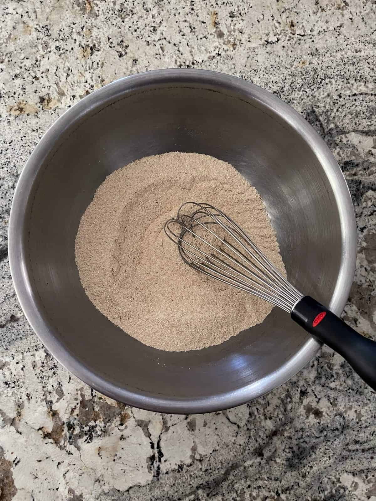 Whisking quinoa flour, baking powder, cinnamon, ginger, baking soda, salt and nutmeg in mixing bowl.