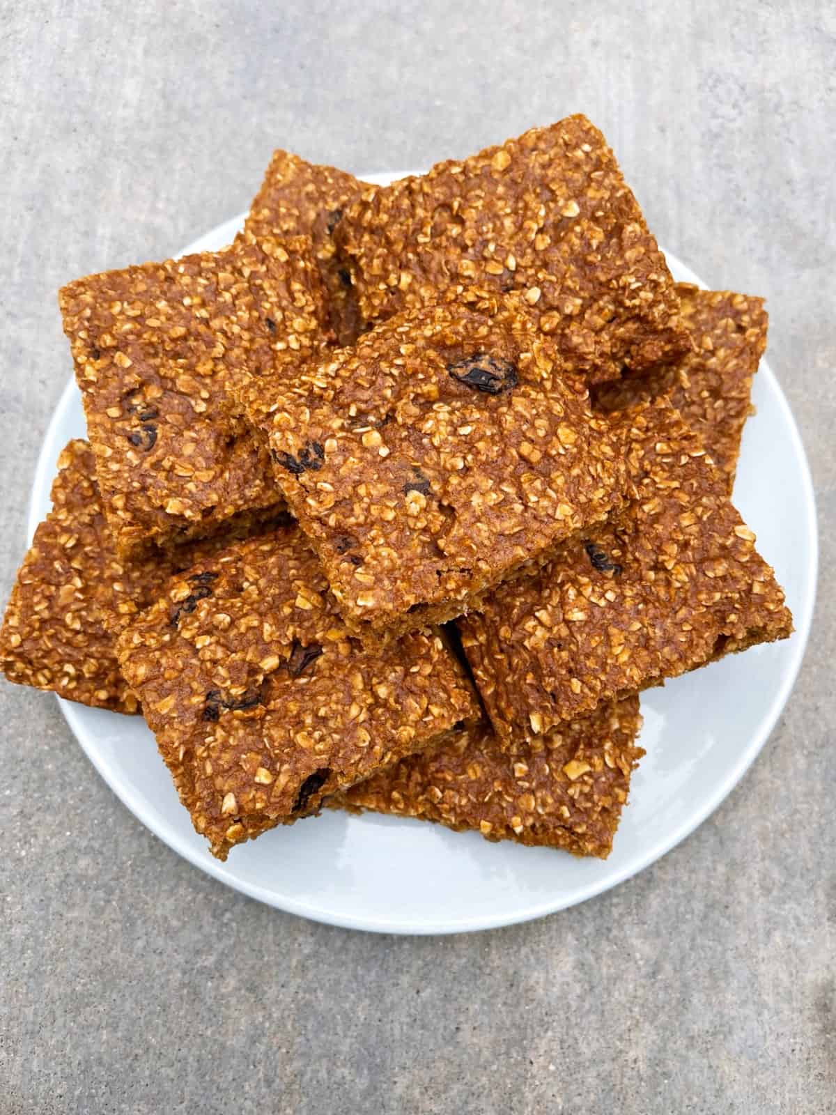 Stack of baked cinnamon-raisin oatmeal squares on serving platter.