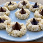 coconut macroon cookies topped with chocolate kisses arranged on a white round plate with title text for pinterest pin