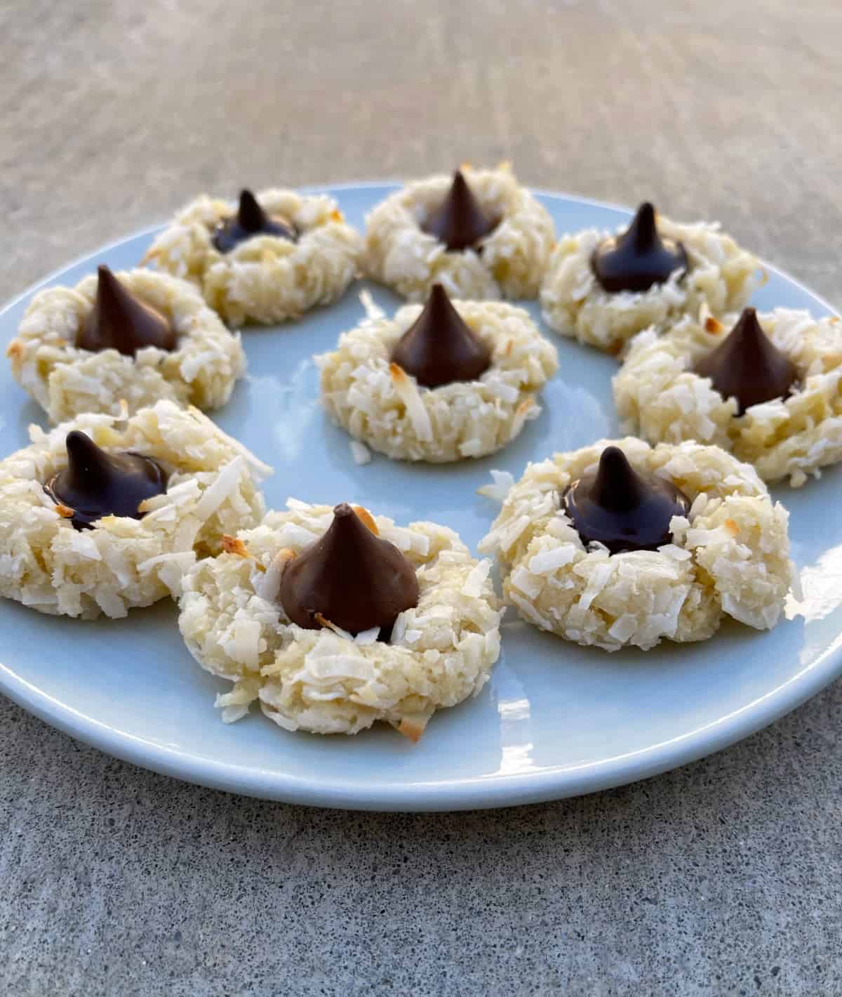 Coconut macaroon kiss cookies on round serving plate.