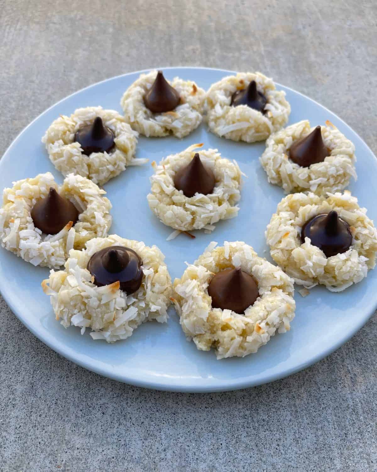 Fresh baked coconut macaroon kiss cookies on round blue plate.