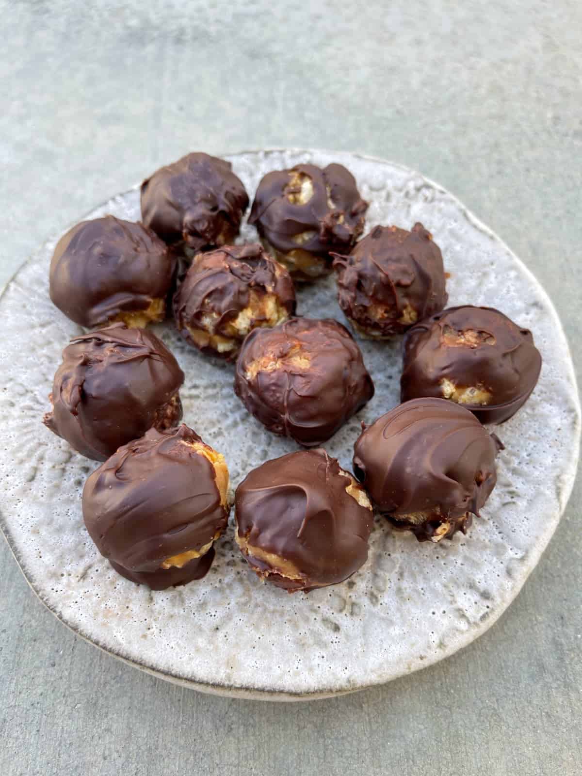No-bake chocolate peanut butter candy bon bons on ceramic plate.