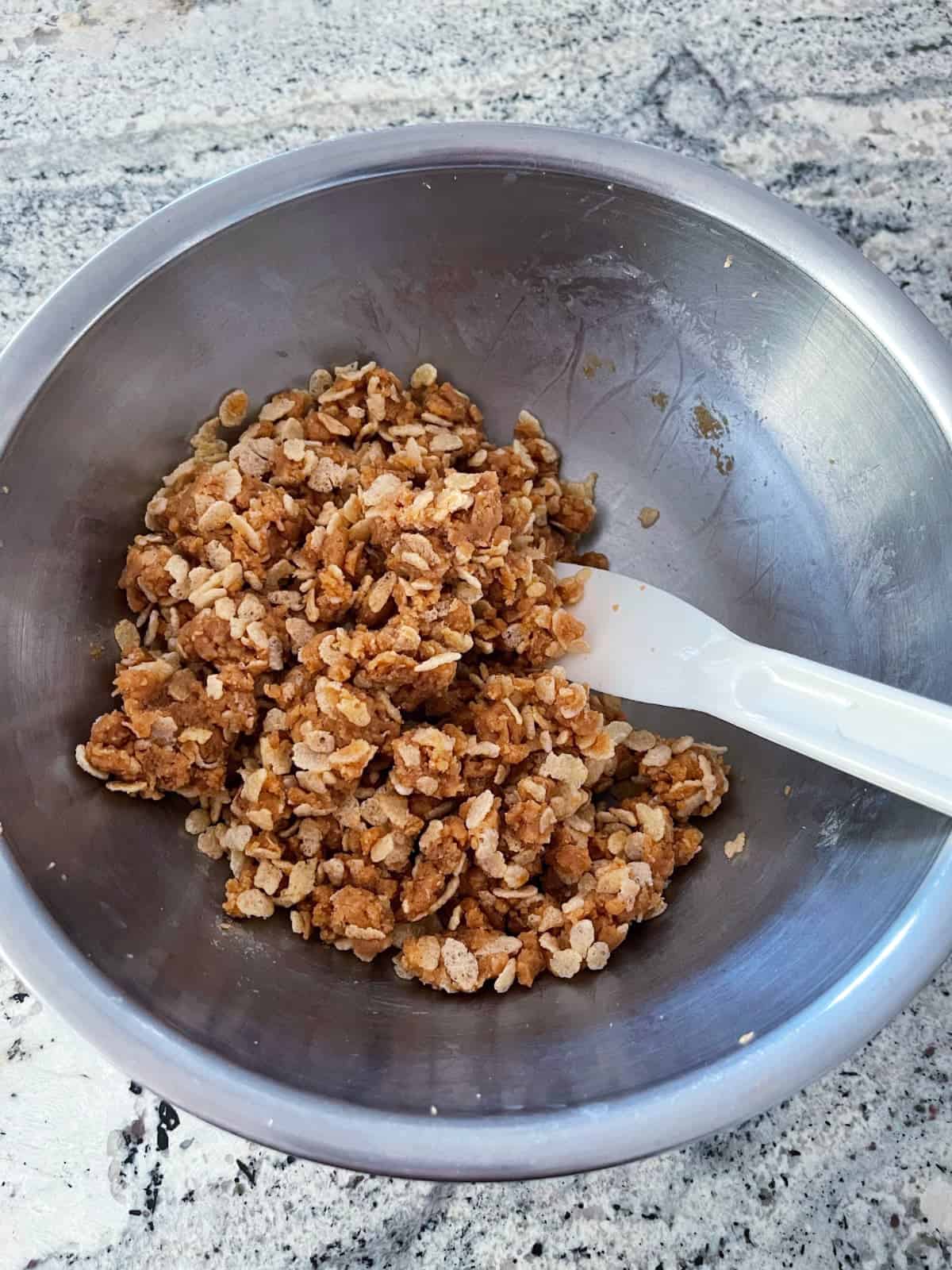 Folding crispy rice cereal into peanut butter bon bon mixture.