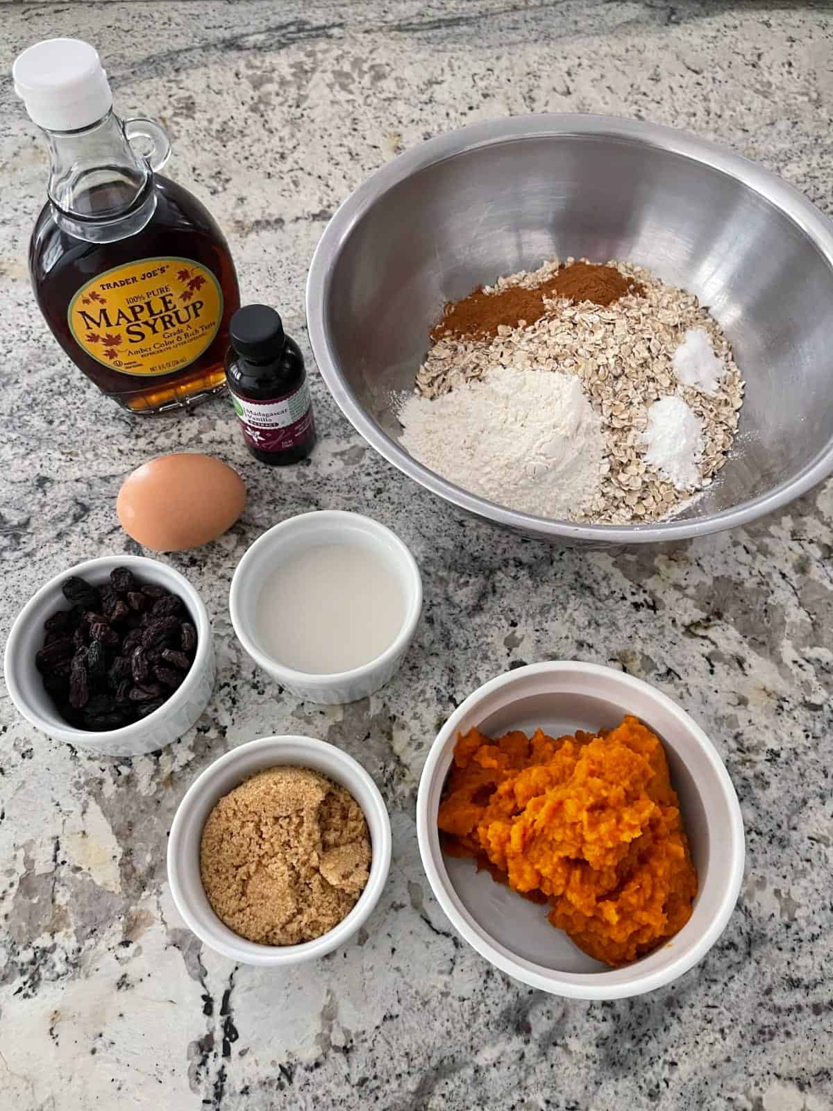 Ingredients including maple syrup, vanilla extract, raisins, egg, almond milk, brown sugar, pumpkin puree, oats, cinnamon and flour.