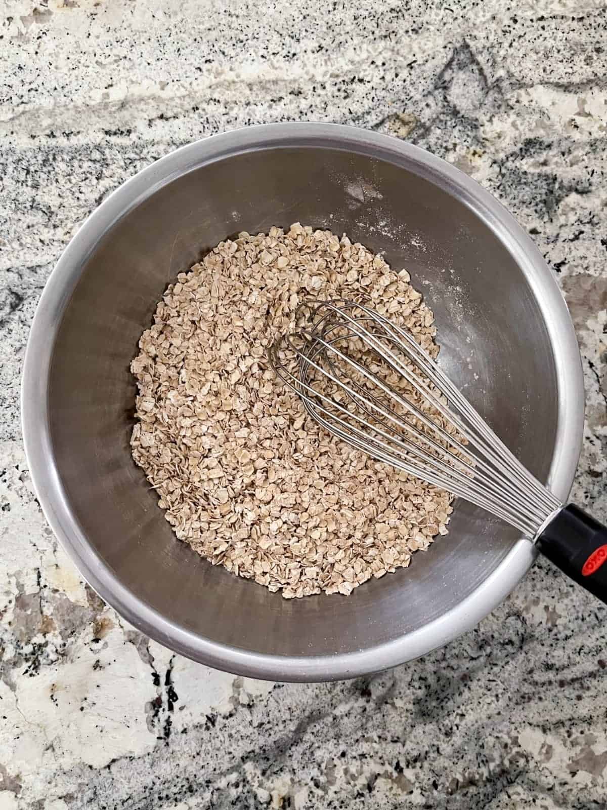 Whisking quick oats, flour, cinnamon, baking powder and baking soda in mixing bowl.