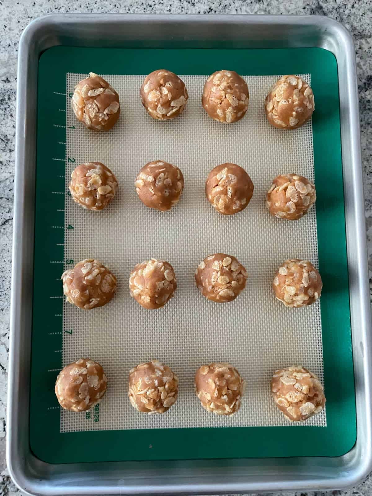 Undipped crispy peanut butter bon bons on silicone liner on small baking sheet.