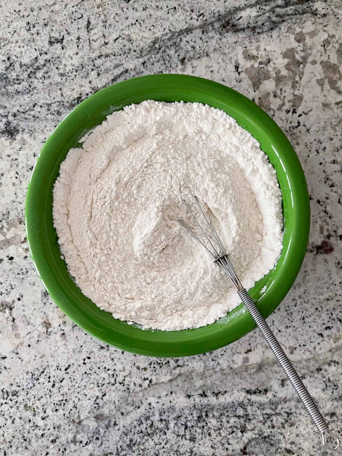 Whisking flour, baking powder and salt in green bowl.