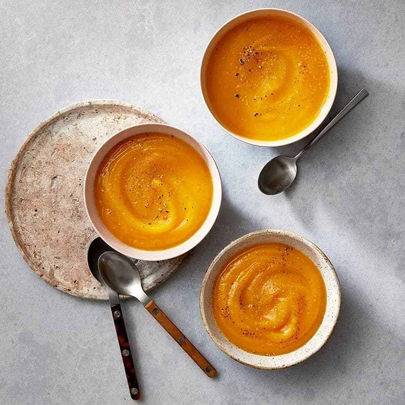 3 bowls of ww carrot apple soup with spoons.