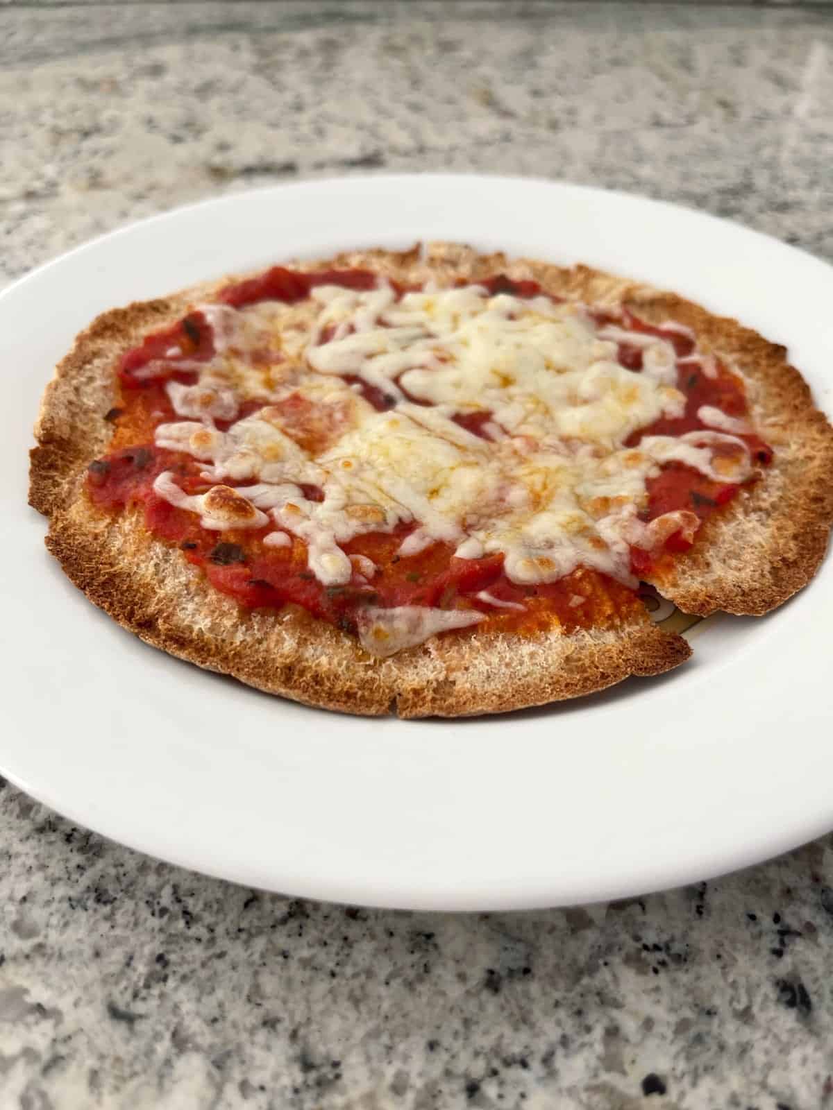 Crispy pita cheese pizza on white plate.