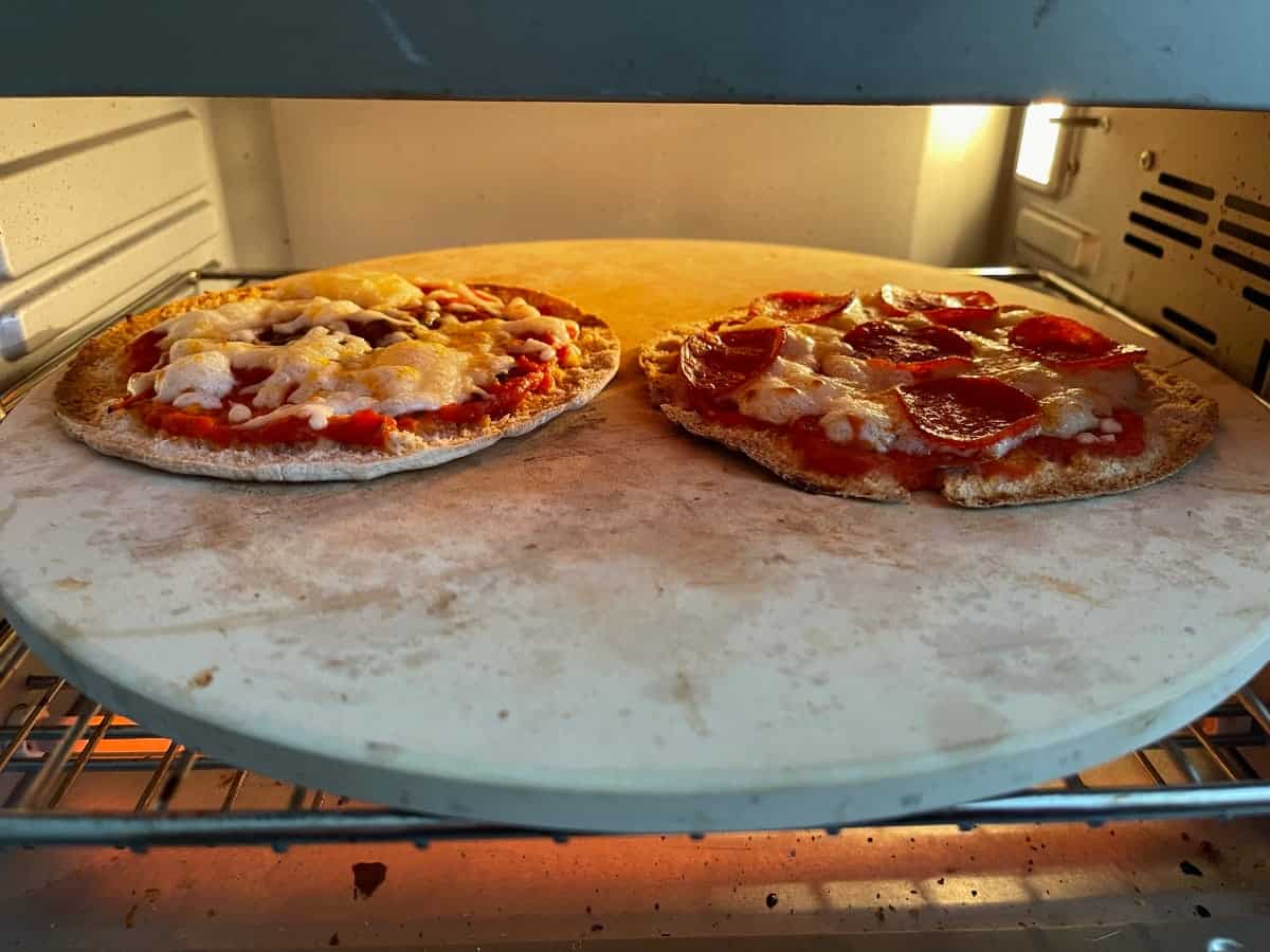 Baking cheese and turkey pepperoni pita pizzas on pizza stone in toaster oven.
