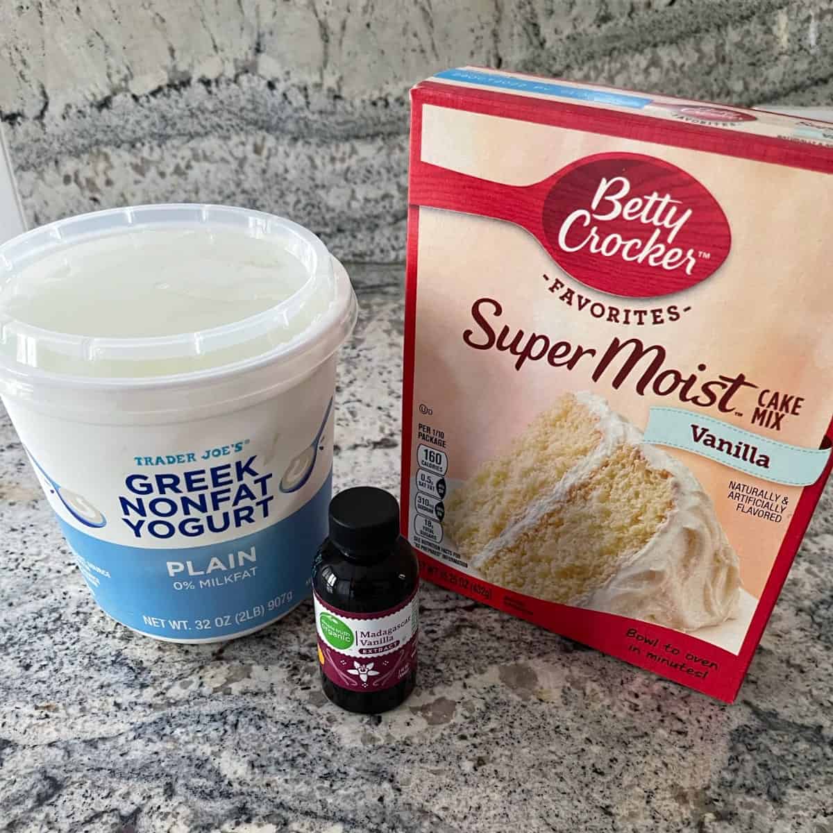 Box of Betty Crocker Super Moist Vanilla Cake Mix, bottle of vanilla extract and container of plain nonfat Greek yogurt.