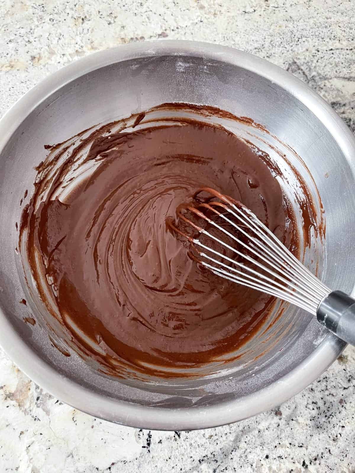 Whisking chocolate cupcake batter in mixing bowl.